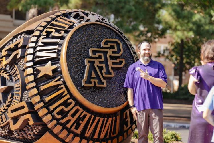 An attendee takes a photo in front of the new Stephen F. Austin State University ring statue during the Centennial Ring Plaza dedication event Monday.