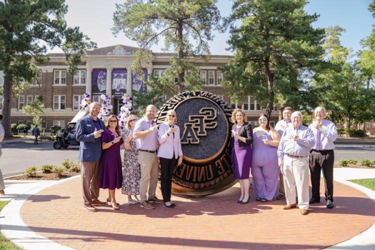 Board members for Stephen F. Austin State University’s Alumni Association pose in front of the SFA ring statue during the Centennial Ring Plaza dedication event Monday. 
